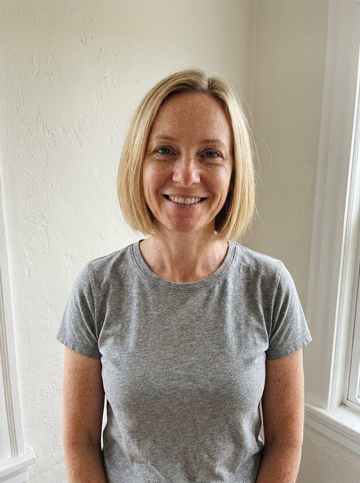 A phone photo of a woman with a blonde bob in a grey t-shirt